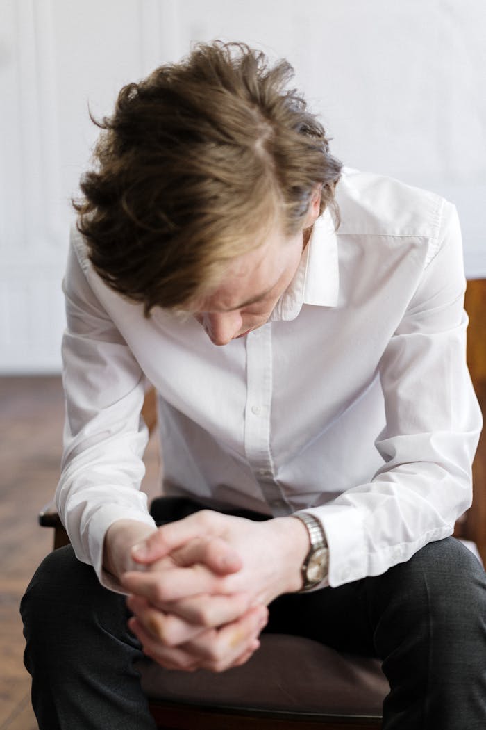 Woman in White Dress Shirt and Blue Denim Jeans Sitting on Chair