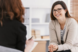 Happy woman during successful psychotherapy with counselor at cl